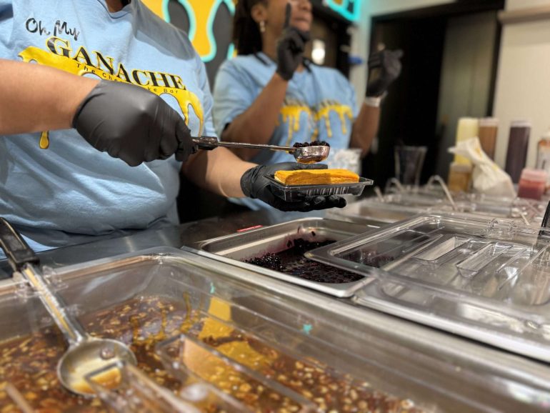 Workers serving toppings at Oh My Ganache Cheesecake Bar in Charlotte, NC
